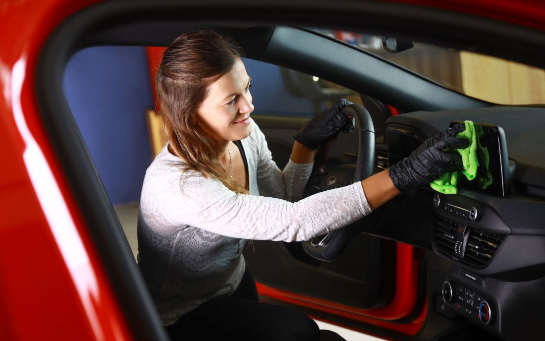 Eine Mitarbeiterin reinigt den Innenraum eines Autos